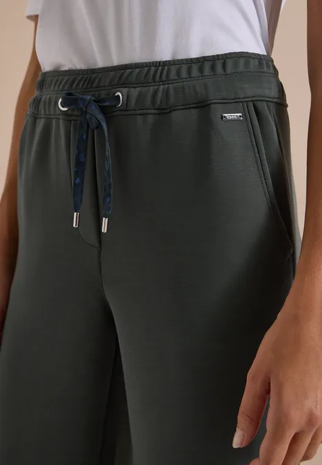 Dunkelgrüne Jogginghose mit elastischem Bund, Kordelzug und seitlichen Eingrifftaschen, kombiniert mit weißem T-Shirtansatz.