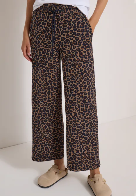 Pantalon ample à imprimé léopard, jambes larges, associé à des mocassins beiges confortables.