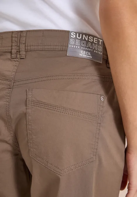 Rückenansicht einer Person in sandfarbenen Chinohosen mit 'SUNSET'-Label am Bund.