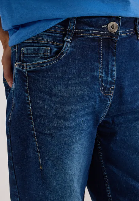 Nahaufnahme einer Person in dunkelblauer Jeans mit Knopf, Reißverschluss und vorderer Taschen.
