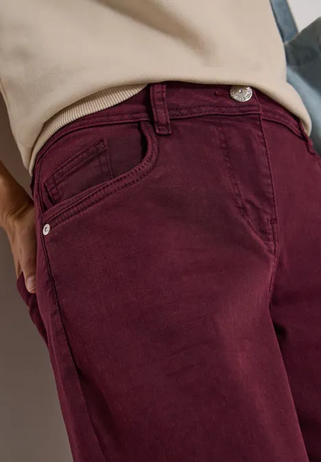 Gros plan d'une personne portant un pantalon bordeaux et un haut beige.