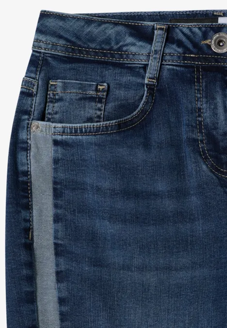 Gros plan d'un jean bleu avec passants de ceinture, poche avant et bouton visible.