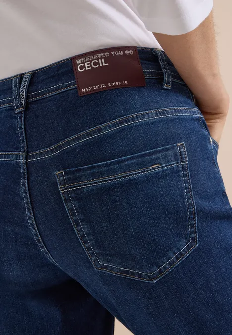 Vue arrière d'une personne en jean bleu avec poche plaquée et étiquette de marque à la taille.
