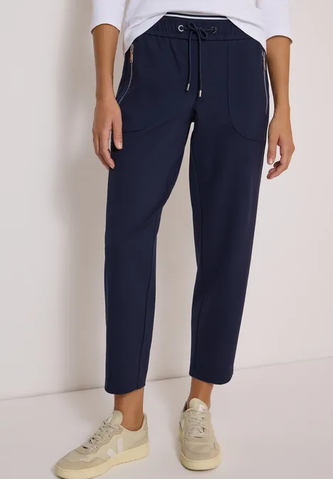 Dunkelblaue, knöchellange Jogginghose mit Tunnelzug und Taschen, dazu helle Sneaker.