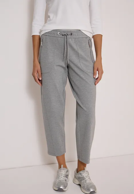 Frau trägt graue Hose mit Kordelzug und silberne Sneaker.