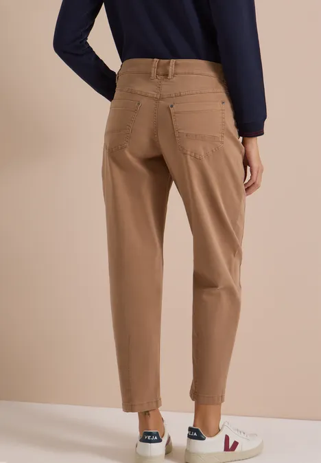Frau von hinten trägt beige Chino-Hosen mit Umschlag, dunkelblaues Oberteil und weiße Sneakers.