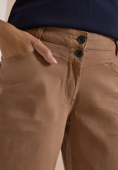 Braune Hose mit zwei Knöpfen vorne, Hand steckt in der Seitentasche.
