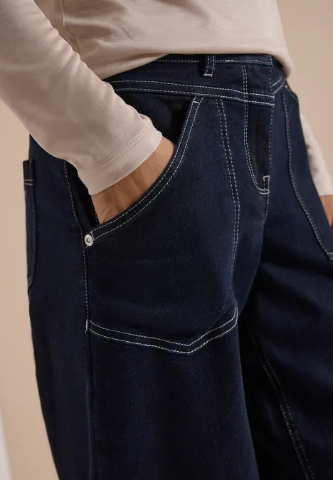 Dunkelblaue Jeans mit kontrastierenden Nähten und Hand in der Tasche.