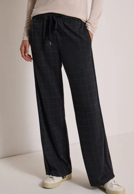 Wide Leg Hose mit Karomuster und Tape urban dark blue Schwarze, karierte, weite Stoffhose mit Kordelzug, kombiniert mit weißen Sneakern.