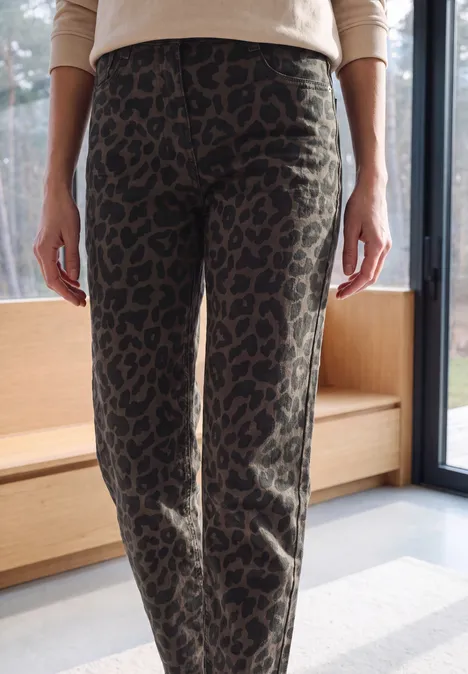 Naheaufnahme einer Person in enger Leopardenhose vor einem Fenster.