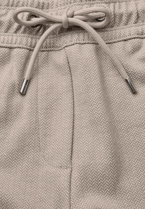 Nahaufnahme eines beigen Sweatpants-Bunds mit Kordelzug und subtiler Fischgrätenstruktur.