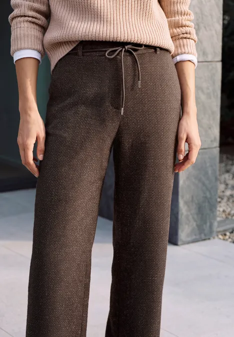 High Waist Wide Leg Hose im Loose Fit truffle brown Person in weitem braunen Strickhose mit Tunnelzug und beigem Pullover vor Steinwand.
