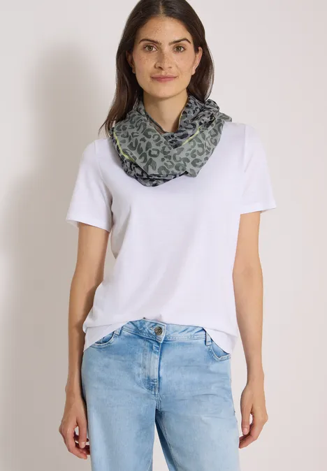 Loop-sjaal in uitgebleekte look met luipaardpatroon dried olive green Frau in weißem T-Shirt, blauen Jeans und gemustertem Schal.