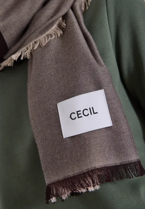 Une écharpe brune à franges avec une étiquette blanche indiquant « CECIL ».