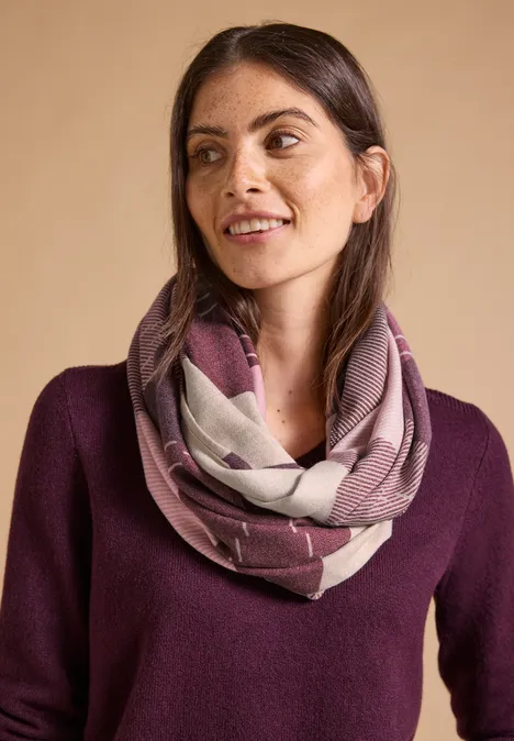 Szalik typu Loop z wzorem argyle berry red Kobieta o ciemnych włosach nosi wzorzysty komin i fioletowy sweter, delikatnie się uśmiecha.