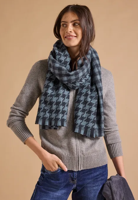Przytulny szalik z frędzlami i wzorami dark navy blue Kobieta w szarym swetrze, dżinsach i kratkowanym szalu, trzyma ciemny płaszcz