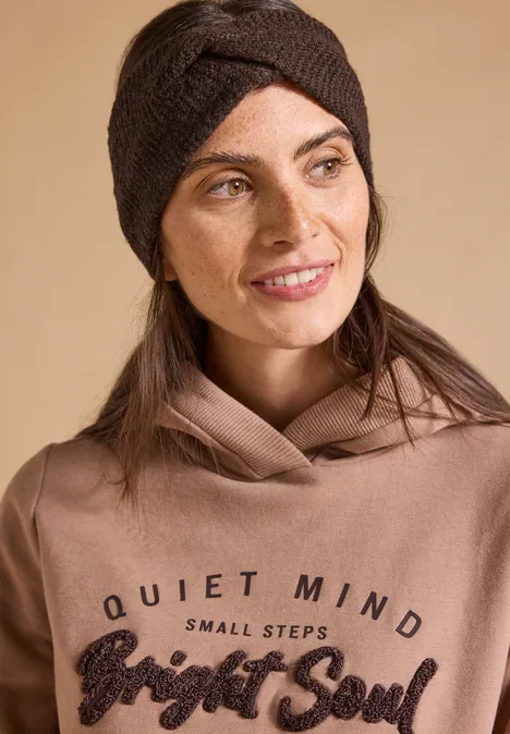 Kobieta w brązowej opasce i bluzie patrzy w bok; napis 'Quiet Mind Small Steps Bright Soul'.