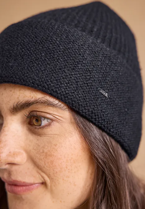 Zbliżenie kobiety w granatowej dzianinowej czapce typu beanie i brązowych oczach.