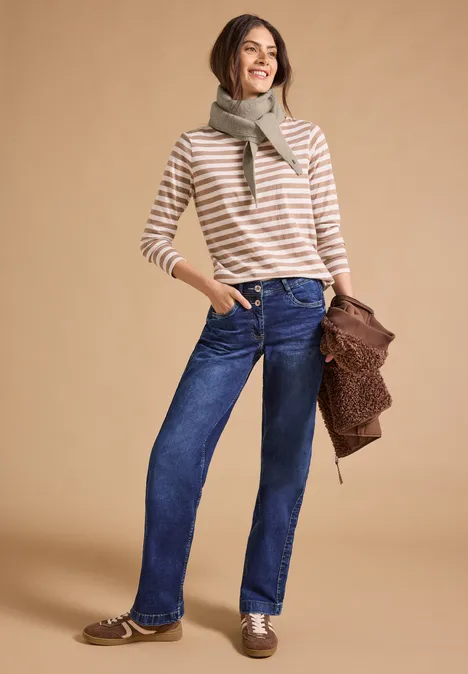 Écharpe à motif mélangé en forme de losange powder beige melange Frau in gestreiftem Shirt, Jeans und Schal, hält Tasche.
