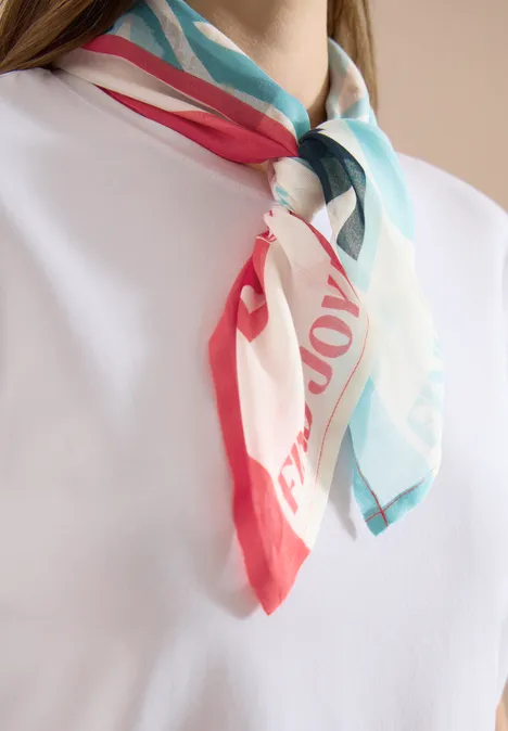 Wit T-shirt met een kleurrijk sjaaltje (rood, turkoois en wit) elegant geknoopt om de hals