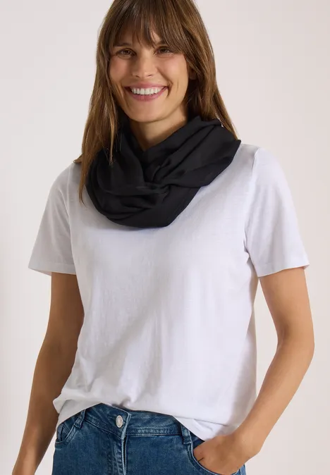 Écharpe Loop unie Black Une femme souriante porte un t-shirt blanc et une écharpe tube noire.