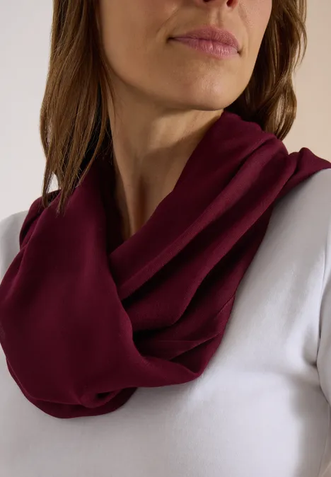Écharpe Loop unie red wine Gros plan sur une personne avec une écharpe tube bordeaux douce sur un haut blanc.