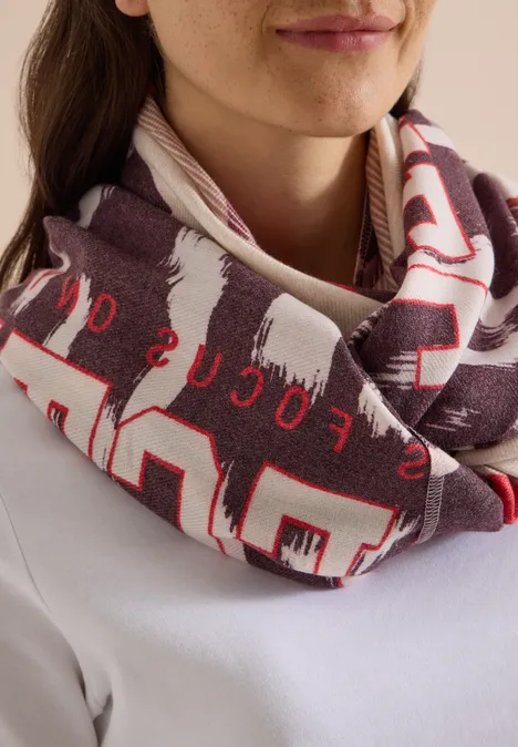 Gros plan d'une femme portant un foulard tubulaire imprimé rouge et blanc autour du cou.