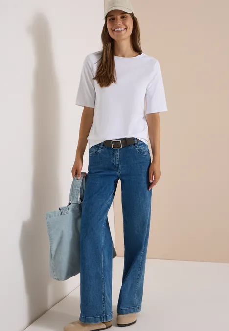 Basic Gürtel mit quadratischer Schnalle Dark Brown Eine lächelnde Frau trägt weißes T-Shirt, weite blaue Jeans, Gürtel und hält eine helle Jeans-Tasche.