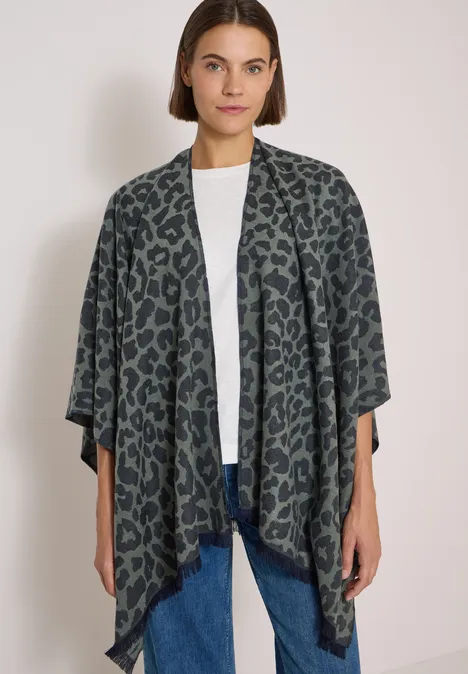 Cape mit Leo-Muster dried olive green Frau in weißem Shirt und Jeans trägt offen fallenden dunkelgrünen Cardigan mit Leopardenmuster.