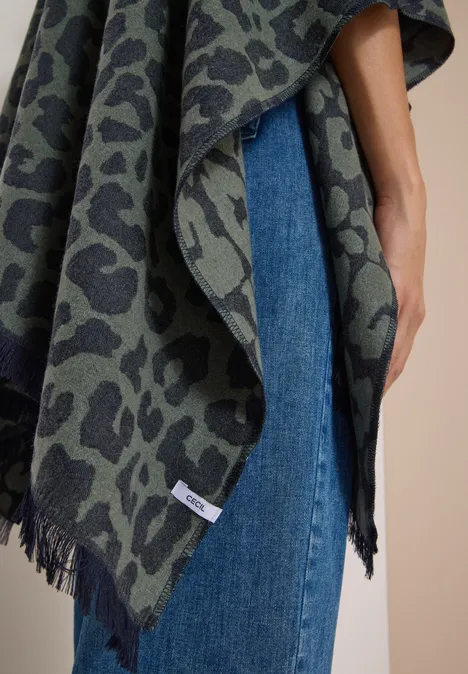 Cape mit Leo-Muster dried olive green Eine Person trägt einen grün-grauen Poncho mit Leopardenmuster über blauen Jeans.
