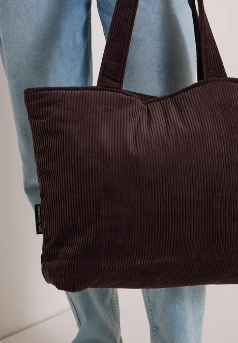 Personne en jean tient un sac marron en velours côtelé