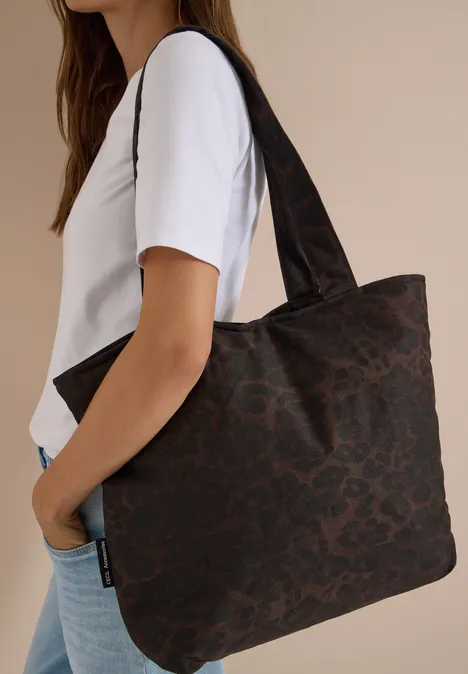 Een vrouw draagt een grote donkerbruine shopper met luipaardprint.