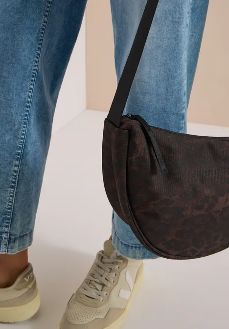 Blaue Jeans, beiger Sneaker und halbrunde braune Umhängetasche an einer Person.