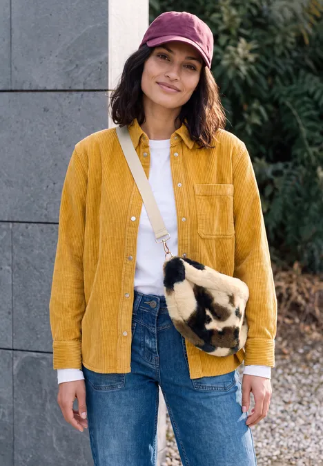 Umhängetasche pearl beige Junge Frau in gelbem Hemd, Jeans und rosa Cap trägt eine flauschige Tiertasche.