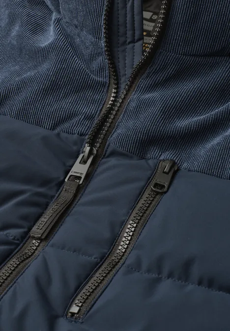 Detailansicht einer dunkelblauen Jacke mit zwei Reißverschlüssen und unterschiedlichen Stofftexturen.