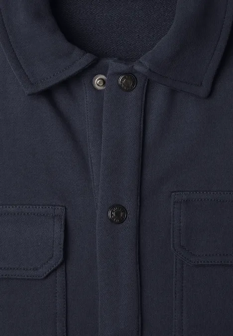 Marineblauwe jas met overhemdkraag, twee borstzakken met klep en knoopsluiting.