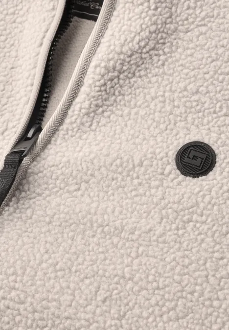 Veste en peluche avec col montant et fermeture à zip classic beige Gros plan d'une veste polaire crème avec zip et petit logo rond