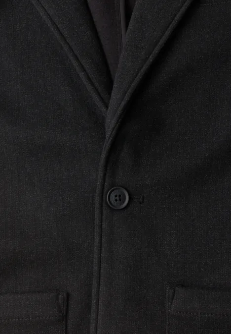 Manteau en laine noir à col tailleur, fermeture à un bouton et deux poches passepoilées.
