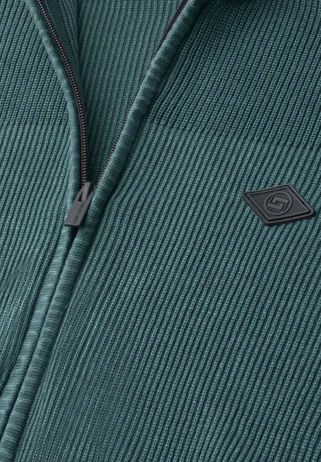 Vest met opstaande kraag en een mix van texturen cold blue Close-up van een donkergroene, geribbelde gebreide jas met rits en klein logo op de borst.