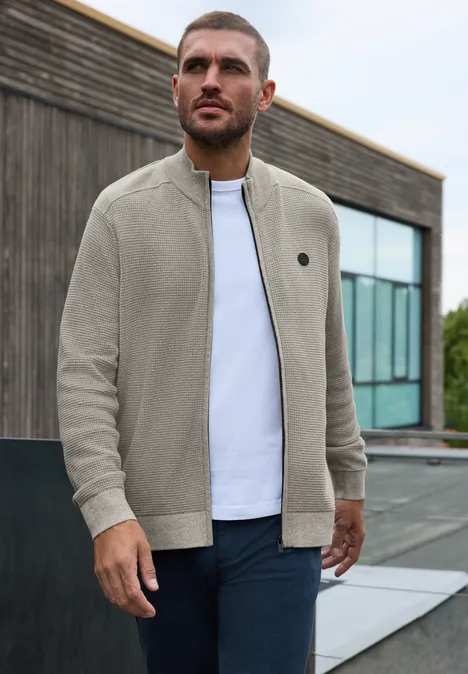 Strickjacke mit Stehkragen und Struktur bright beige melange Ein Mann steht vor einem modernen Gebäude und trägt eine bequeme, hellgraue Zip-Jacke über weißem T-Shirt.