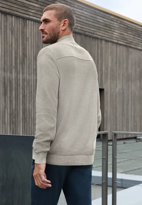 Strickjacke mit Stehkragen und Struktur bright beige melange Ein Mann steht auf einem Dach vor einer Holzfassade, trägt eine graue Strickjacke und schaut seitlich.