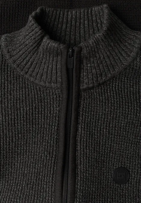 Naheaufnahme eines dunklen Strickpullovers mit hohem Kragen und Reißverschluss.