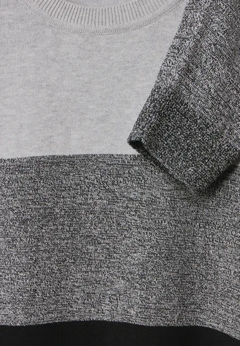 Gros plan sur un pull à rayures grises et noires.