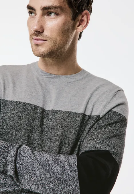 Homme en pull gris regarde à gauche.