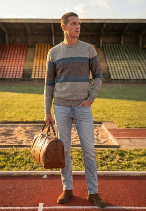 Trui met ronde hals en streepjespatroon bright beige melange Een man in een gestreepte trui met reistas staat op de atletiekbaan voor kleurrijke tribunes.