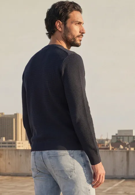 Trui met ronde hals en schouderdetail dark basic blue Een man in jeans en trui staat op een dak en kijkt uit over de stad.