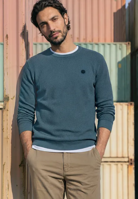 Trui met ronde hals en schouderdetail cold blue Een man in een casual trui en chino’s voor kleurrijke containers.