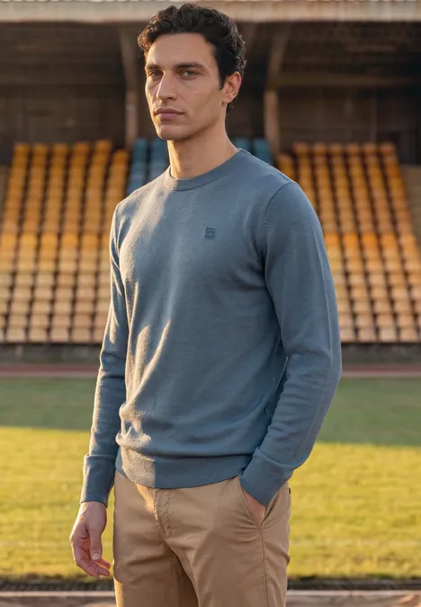 Eenvoudige trui met ronde hals in effen kleur cold blue Man in lichtblauwe trui en beige broek voor lege tribunes.