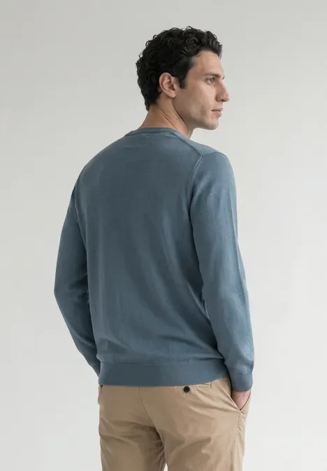 Eenvoudige trui met ronde hals in effen kleur cold blue Een man in een blauwgrijze trui en beige broek, zijwaarts staand met een hand in zijn zak.