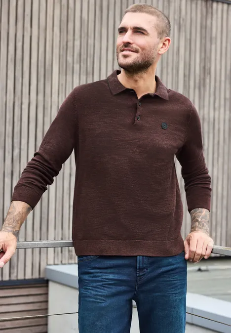 Gebreid poloshirt in mouliné-look maroon brown Man in een bruine polo-trui en blauwe jeans, staat ontspannen voor houten lamellen